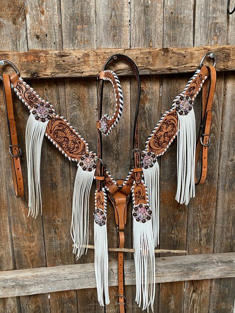 Browband, one ear, wither strap and breastcollar is floral tooled whipstitch style. They are decorated with copper AB crystal conchos/buckles and white fringe. Full Horse size Measurements Headstall measurements : bit to bit - 36" shortest setting : 44" longest settingBrowband measures 15" acrossBreastcollar measurements - From Center Ring to D Ring -16"Breastcollar including toggles : shortest settings - 26" : Longest settings -29" Lifetime guarantee on all crystals.Buy Together or Separate BRO Wither Straps For Horses, Western Tack Sets Barrel Racing, Tack Sets Western, Horse Tack Sets, Western Riding Tack, Western Tack Sets, Barrel Racing Tack Sets, Barrel Racing Tack Rodeo, Bling Horse Tack