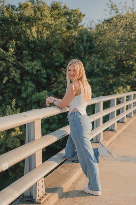 blond teen girl poses with one leg kicked back, smiling over her shoulder at the camera as she leans on a bridge railing. Indoor Senior Pictures, Casual Senior Pictures, Cute Modeling Poses, Senior Outfit Ideas, Spring Senior Pictures, Senior Portrait Outfits, Senior Portrait Ideas, Senior Pictures Downtown, Senior Photoshoot Poses