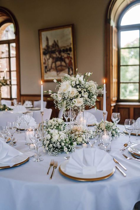 Klassisch elegante Hochzeitsdeko in weiß und gold für runde Tische. In der Mitte werden hohe und flache Blumenarrangements in weiß zusammen mit Stabkerzen in goldenen Haltern aufgestellt. Goldenes Besteck und weiße Teller mit Goldrand komplettieren die Tischdeko. → Jetzt weitere Bilder einer Glam White Wedding bei frauimmer-herrewig.de entdecken. | Konzeption & Organisation: CJ Weddingprojects | Foto: Andi Sommer und Bi Nguyen | Tischdeko Hochzeit weiß gold | #frauimmerherrewig Wedding Decoration White And Gold, Wedding Decor White And Gold, Gold And White Wedding Decorations, White And Gold Wedding Decor, White Wedding Aesthetic, Winter Pool, White Wedding Decorations, Engagement Events, Lights Ideas