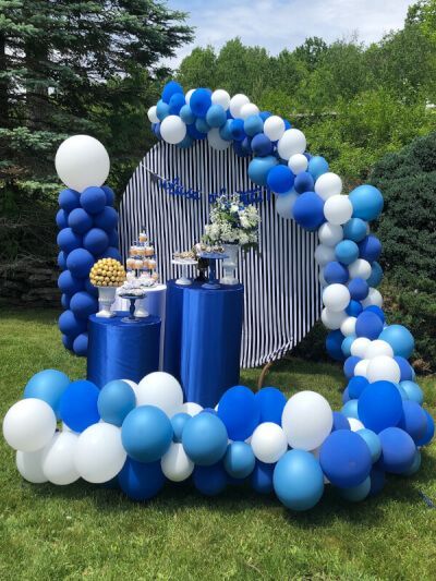 Spread cheerful colors and festive flair all around your outdoor party space with our easy to assemble balloon pillar stands and further adorn them with royal blue/white round latex balloons using balloon garland tape. Set the backdrop using black/white stripe satin tablecloth and add a dash of floral charm by topping the tables with a lovely floral arrangement using our artificial daisy & white baby's breath artificial flowers in our planter pots along with your scrumptious delights. Wedding Arch Balloons, White And Blue Party Decorations, Decor With Balloons, Floral Columns, Outdoor Graduation Party Decorations, Backdrop Setup, Outdoor Graduation Party, Party Ambiance, Balloon Pillars