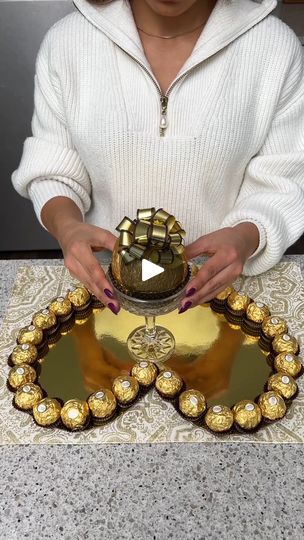 1M views · 26K reactions | Ferrero Rocher Bouquet | A proposal she can't say no to 🌹 | By The Shaba Kitchen | I'm going to start by gluing some fero rochers onto our heart. I'm just using a glue gun and just putting a little bit in the bottom of each one and then I'm putting them right beside each other all around and there we go. Now I'm going to do our last one here to complete our beautiful heart. Alright now I'm going to take a big giant fero rocher and we're going to remove the chocolate part. Put that in our cup here. And then we're going to take some more of that glue. Put a little bit in the base. And then we're just going to glue this right in the middle Just like that. And then we're going to take some more of the mini ones. And we're just going to start filling up all that empt Wedding Parcels, Ferrero Bouquet, The Shaba Kitchen, Rocher Bouquet, Ferrero Rocher Bouquet, Everything Stays, Gorgeous Prom Dresses, Beautiful Red Roses, Chocolate Bouquet