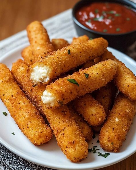 Irresistible Mozzarella Cheese Sticks 🧀🍅 Ingredients: 12 mozzarella string cheese sticks, cut in half 1/2 cup all-purpose flour 2 large eggs 2 tablespoons milk 1 1/2 cups Italian-style breadcrumbs 1 teaspoon garlic powder 1 teaspoon dried parsley 1/2 teaspoon salt 1/4 teaspoon black pepper Oil, for frying Marinara sauce, for dipping Instructions: Place the cut mozzarella sticks on a baking sheet lined with parchment paper. Freeze for at least 1 hour until solid. Prepare three bowls: one w... Air Fryer Mozzarella Sticks, Homemade Mozzarella Sticks, Mozzarella Cheese Sticks, Black Pepper Oil, Dried Parsley, String Cheese, Sweet Dishes Recipes, Mozzarella Sticks, Cheese Sticks