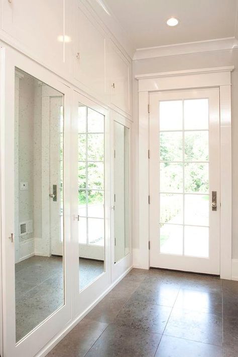 Long mudroom features a row of closets finished with mirrored doors. Long Mudroom, Rustic Mudroom, Board Backsplash, Cottage Laundry, Mirrored Closet, Transitional Closet, Transitional Laundry Room, Grey Front Doors, Mirror Closet