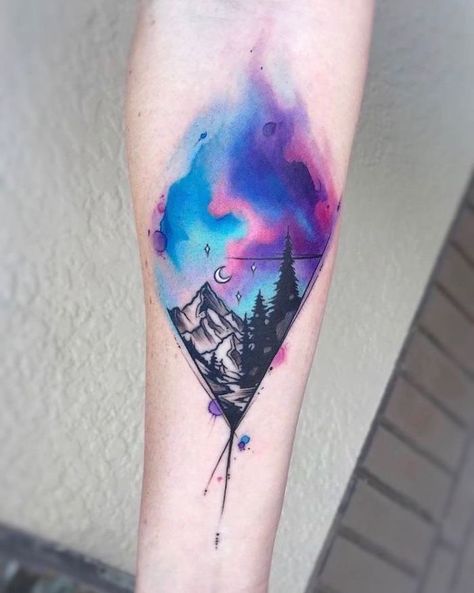 mountain-landscape-with-trees-watercolor-galaxy-sky-above-them-outer-space-tattoo-forearm-tattoo Watercolor Mountains Tattoo, Sky Tattoos, Watercolor Rose Tattoos, Colorful Tattoo, Kunst Tattoos, Galaxy Tattoo, Forest Tattoos, Muster Tattoos, Landscape Tattoo