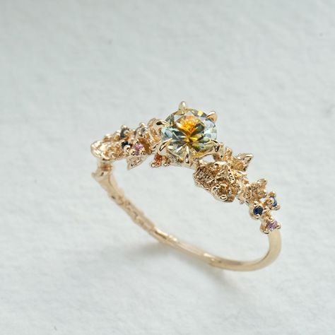 The ethereal and enchanting dahlia, sweetly pulled from a peachy fairytale. Featuring a 5mm parti Montana sapphire— each stone a one-of-a-kind, natural blend of peach/apricot and silvery/greenish hues. Just like the dahlias that inspired it, the sapphires’ swirling hues are dreamy and glistening. Features a 5mm “kaleidoscope” Montana Parti sapphire (each stone is unique, with peach and silvery/greenish hues)A sprinkling of a 0.9mm orange sapphire, 1mm orange sapphire, 1.2mm orange sapphire, 1mm Cottagecore Wedding Ring, Earthy Wedding Rings, Laurie Fleming, Light Blue Sapphire, Earthy Wedding, Cute Engagement Rings, Future Engagement Rings, Montana Sapphire, No Code