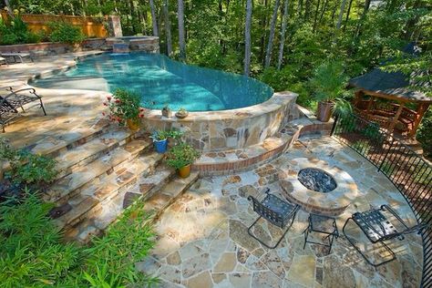 Pool surrounded by stone and nature looks so great! Hillside Pool, Pools Design, Kleiner Pool Design, Sloped Yard, Sloped Backyard, Custom Swimming Pool, Stone Steps, Small Pool Design, Swimming Pools Inground