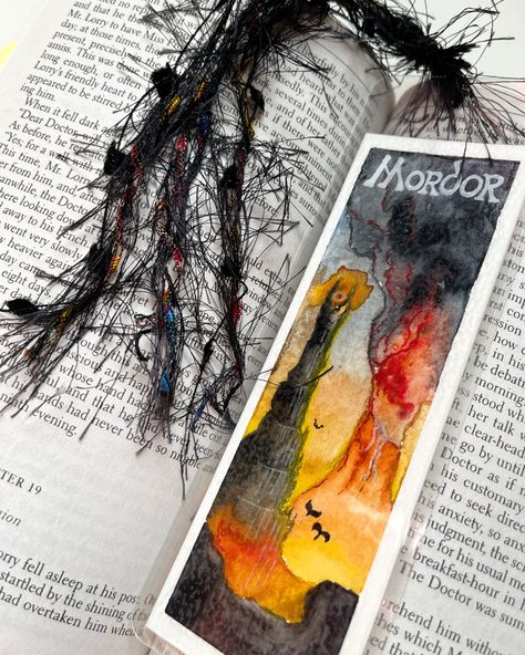 2.5” x 7” bookmark depicting scene of Mordor from Lord of the Rings - a fiery mountainous area with an active volcano painted in orange and black colors. Laminated in clear plastic, 10 mil thick. A black tassel is tied and looped through the plastic. Lotr Bookmark Diy, Lord Of The Rings Gift Ideas, Watercolor Art Bookmarks, Lotr Bookmark, Lord Of The Rings Watercolor, Lord Of The Rings Bookmark, Lotr Gifts, Bookmark Watercolor, Painted Bookmarks