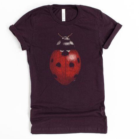 Did you know that one ladybug can eat up to 5,000 insects in its lifetime? Luckily, this shirt doesn't eat insects, or anything at all! Show your love for these cute beetles without the worry of losing it in the house. -------------- Every item sold plants 1 tree- Eco-Friendly shirts-------------- 100% combed and ring-spun cotton (heather colors contain polyester)- Soft, stretchy material--not heavy or rigid- Fabric weight: 4.2 oz (142 g/m2)- Shoulder-to-shoulder taping- Side-seamed------------- Pretty T Shirts, Insect Outfit, Ladybug Clothes, Indie Shirts, Bug Clothes, Ladybug Shirt, Shirts To Buy, Weird Clothes, Bug Shirt