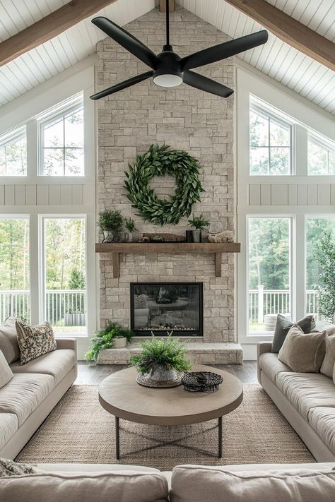 Modern farmhouse living room with stone fireplace a big green wreath above the mantel near vaulted ceiling ceiling in reclaimed wood slats large. Check out all of these dream farmhouses that will have you drooling with rural living fantasies and mooing with joy! Fireplace To Ceiling Stone, Farmhouse Living Room Stone Fireplace, Fireplace In High Ceiling Room, Wooden Mantle On Stone Fireplace, White House With Greenery, Fireplace For Vaulted Ceiling, Fireplaces With Cathedral Ceilings, Living Room With Windows And Fireplace, Living Room Designs Stone Fireplace