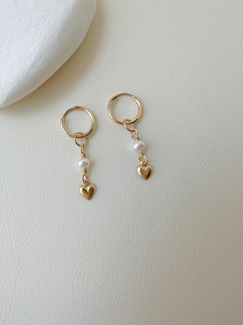 "These cute freshwater pearl and mini heart earrings are handmade from 14k gold filled, the pearl and heart charms can be removable. -------------------------------------------------------- >>  Material: 14k gold filled  hoop and tiny heart  >> Length: 3cm >>  Hoop Diameter: 10mm >>  Pearl Diameter: 3-3.5mm >>  Sensitive skin friendly & tarnish resistant ------------------What is gold filled ------------------ Most of our findings and wires are made with 14k gold filled.\"Gold-filled\" is a USA industry standard that legally requires 5% pure gold by weight. It is a solid layer of gold bonded to another metal through heat and pressure. It does not wear off or turn colours over time, and if taken care of properly it can last a lifetime.Gold-filled jewellery is a cheaper, yet the best alterna Cute Charm Earrings, Jewelry Inspo Earrings, Simple Earing, Jewellery Charms, Pearl Heart Earrings, Cute Jewellery, Handmade Pearl Jewelry, Pretty Jewelry Necklaces, Mini Earrings