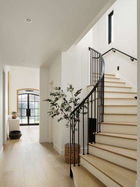 Just a hallway, but it also happens to be one of our favorite shots at our #LADLaJollaRemodel with @coatinc. It features our custom designed entry doors and  curved staircase.  We maintained a nod to the Spanish architectural influence through the use of arches and iron, while honoring our clients desire for a more contemporary space. Stairs In Great Room, How To Modernize A Traditional Home, Modern Farmhouse Stairs, Modern Traditional Interior Design, Staircase In Living Room, Modern Traditional Homes, Traditional Modern Home, Staircase Hallway, Modern Traditional Decor