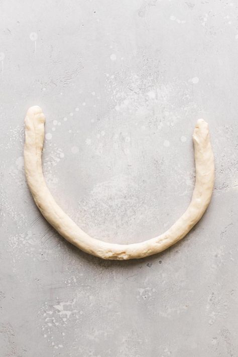 A roll of raw pretzel dough formed into a U shape. Live Well Bake Often, Pretzel Dough, Soft Pretzel Recipe, Pretzel Shape, Pretzel Recipe, Baking Soda Bath, Homemade Pretzels, Homemade Soft Pretzels, Soft Pretzel