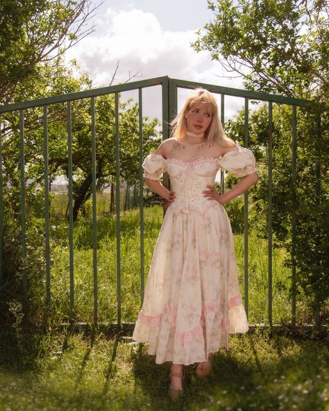 ‘ It was June, and the world smelled of roses. The sunshine was like powdered gold over the grassy hillside ‘ 🤍🌱💐✨🪻🌼🌷🍃 Do you think this gate take us to a secret garden? 🤔 — Dresses : from @lacemadeofficial — Shoes : from @ecosusi_vintage use ‘Reivaille30’ for a discount at the checkout (link in bio) ✨ . . 🏷️ #fairytalephotography #gardenfairy #enchantedliving #poetryofsimplethings #spring #seasonaltales #aesthetic #aseasonalstory #searchwandercollect #vintage #romantic #coquette #little... Cottagecore Victorian Dress For Spring Daywear, Feminine Spring Victorian Daywear Dress, Spring Cottagecore Vintage Dress With Ruffles, Spring Coquette Dress With Built-in Bra, Gunne Sax Sundress, Romantic Coquette, Garden Dresses, A Secret Garden, Princess Core