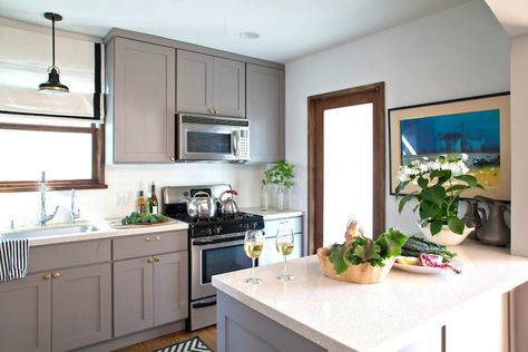 Beautiful gray kitchen with gray cabinets painted a warm gray, Benjamin Moore Eagle Rock, accented with antique brass hardware paired with speckled countertops and stacked white tile backsplash. Benjamin Moore Kitchen, Diy Kitchen Cabinets Painting, Kitchen Cabinet Trends, White Tile Backsplash, Best Kitchen Cabinets, Eagle Rock, Kitchen Cabinet Hardware, Grey Kitchen Cabinets, Kitchen Cabinet Colors