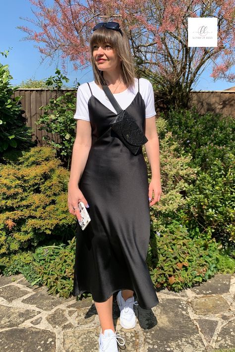 To get more wear out of your black slip dress, try styling with a bodysuit and trainers. Here I've teamed it up with a hip bag by INYATI for a more casual yet contemporary outfit. Monochrome styling is so chic, it's perfect for a daytime city trip, travelling outfit or simple brunch date  with girlfriends. #daytimestyling #blackslipdress #slipdress #brunchoutfit #travelchic #citystyle Daytime City Outfit Summer, Dress Down Silk Dress, Black Silk Dress Slip, Slip Dress And Converse, Satin Dress And T Shirt, Satin Long Dress Outfit, Black Satin Dress Casual Outfit, Monochrome Dress Outfit, Satin Dress With Shirt Under