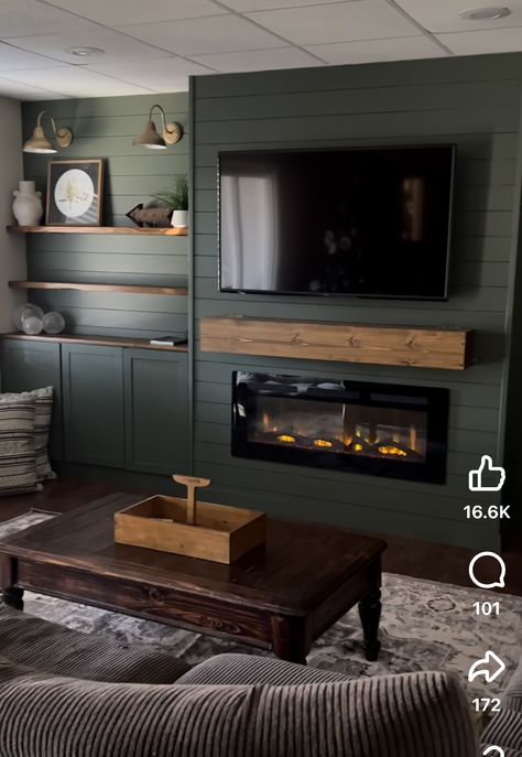 Dark Green Shelves Living Room, Fireplace Wall Ideas With Tv Shiplap, Green Accent Wall Living Room Fireplace, Cozy Basement With Fireplace, Lights On Side Of Fireplace, Green Accent Wall With Fireplace, Basement With Fireplace Ideas, Shiplap Fireplace With Shelves On Side, Fireplace Tv Accent Wall