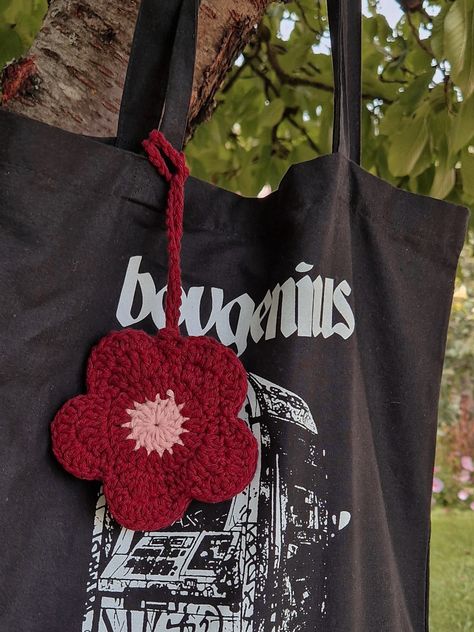 boygenius tote bag with a handmade crochet bag charm in the shape of a flower Knitted Things To Sell, Crochet Bag Decoration, Bag Charm Crochet Pattern, Crochet Flower Bag Charm, Crochet Bag Charm Pattern, Crochet Charm Bag, Crochet Bag Charm Pouch, Tote Bag Charms, Bag Charms Crochet