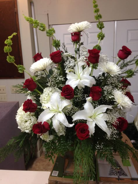 Fresh church arrangement using bells of Ireland, white lilies, white hydrangeas, white spider mums and red roses with some mixed winter greens for the beginning of the Christmas season. First Baptist Church-- November 29, 2015. Southern Traditions-- Booneville, MS--662-728-1876. Designer Matt Rinehart Holiday Flower Arrangements, Winter Flower Arrangements, Winter Floral Arrangements, White Flower Arrangements, Altar Arrangement, Church Altar, Large Flower Arrangements, Artificial Floral Arrangements, Church Flower Arrangements