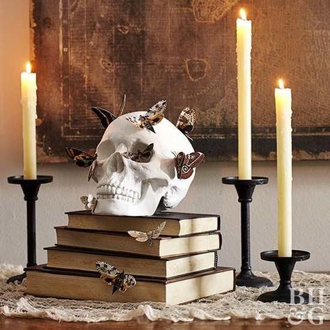 A skull adorned with artificial moths adds spooky style to any space. Try using it as Halloween mantel decor or perching it on a bookshelf. Stack it on old books and embellish with candlesticks to complete the Halloween scene. Porta Halloween, Halloween Mantel Decor, Table Halloween, Halloween Decor Diy, Classy Halloween, Casa Halloween, Halloween Mantel, Costumes Couples, Diy Halloween Decor