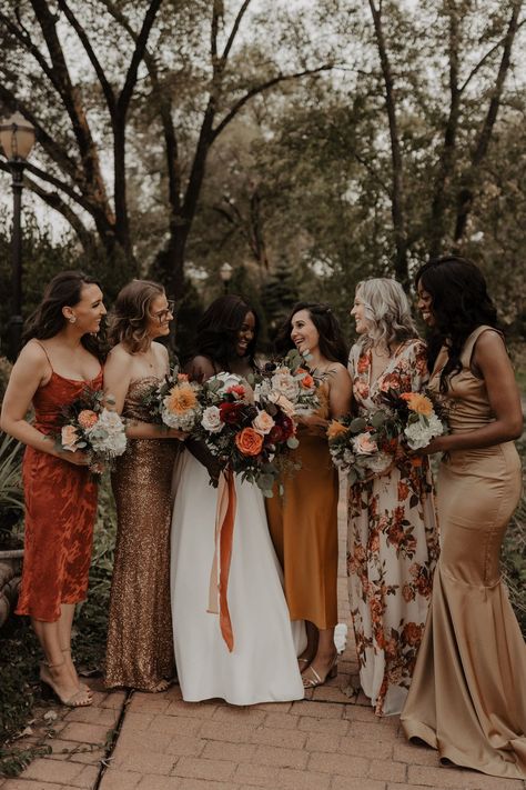 bridesmaids wearing multi colored, earth toned dresses Fall Wedding Mixed Bridesmaid Dresses, Mismatched Patterned Bridesmaid Dresses, Printed Bridesmaid Dresses Fall, Eclectic Bridesmaids Dresses, Fall Wildflower Bridesmaid Dresses, Fall 2024 Bridesmaid Dresses, Moody Fall Bridesmaid Dresses, Boho Bridesmaid Dress Colors, Moody Bridesmaid Dresses Mismatched