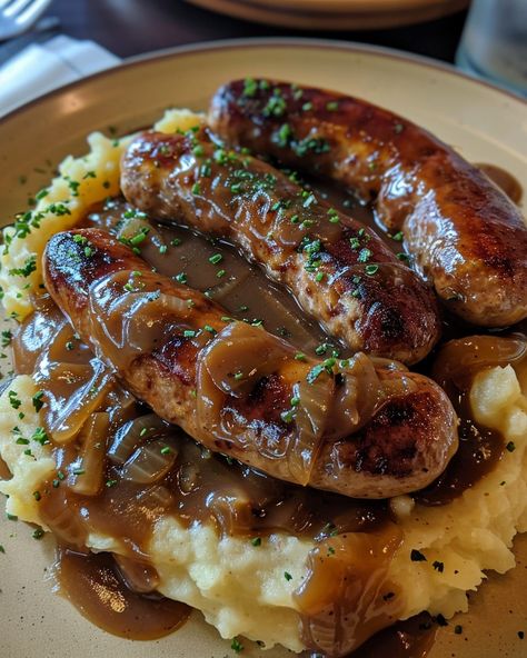 Classic Bangers and Mash with Rich Onion Gravy Ingredients: 8 pork sausages (traditional British bangers) 4 large potatoes, peeled and cut into chunks 4 tablespoons unsalted butter 1/2 cup milk (or more, as needed) Salt and pepper, to taste For the Onion Gravy: 2 large onions, thinly sliced 2 tablespoons unsalted butter 2 tablespoons all-purpose flour 2 cups beef or chicken broth 1 tablespoon Worcestershire sauce Salt and pepper, to taste Instructions: Step 1: Cook t... British Food Recipes, British Bangers, British Meals, Mashed Potatoes With Gravy, Potatoes And Chicken, British Food Traditional, Sausage And Mash, Pork Sausages, Gravy Ingredients