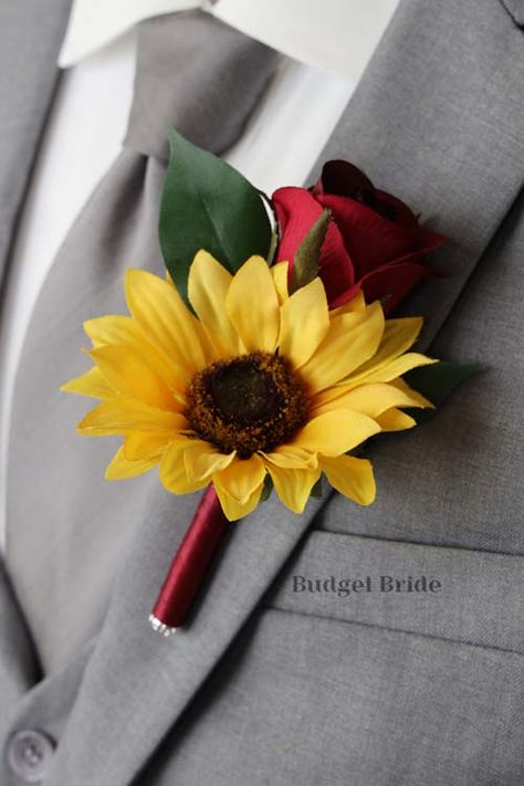 Mens lapel boutonniere with 1 sunflower and 1 wine rose and foliage. The stems of the flowers are wrapped with wine ribbon. Rose And Sunflower Boutonniere, Black And Burgundy Wedding With Sunflowers, Sunflower And Mum Bouquet, Roses And Sunflowers Wedding Decorations, Sunflower And Rose Wedding Decorations, Red And Sunflower Wedding, Maroon And Sunflower Wedding, Sunflower And Rose Wedding Theme, Rose And Sunflower Wedding Theme