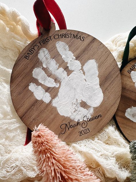 "This is the perfect handprint Christmas ornament keepsake to remember those little handprints forever! Have us engrave their name and date at the bottom of the ornament and if this is their first Christmas we can engrave, \"Baby's First Christmas\" at the top as well.  Choose from Light Maple or Dark Walnut wood. Choose from 3 velvet ribbons: Red, Green or Gold. (Paint is NOT included but any acrylic paint works great on our wood ornaments.) Choose from 3 different sizes: Small: Will fit a hand Handmade Baby Ornaments, Baby Homemade Ornaments, Christmas Gifts From Newborn, Baby Foot Ornament Diy, Baby Handprint Ornament Paint, Grandchildren Christmas Ornaments, Baby Christmas Keepsakes Diy, Baby Christmas Crafts Diy, Baby Craft Ideas Christmas