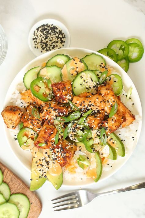 viewed from overhead, a white bowl sits on a white marble counter. The bowl is filled with white rice and topped with avocado slices, cucumber, crispy spiced salmon pieces, and drizzled with spicy mayonnaise. A fork sits below the bowl, and a small bowl of black and white sesame seeds sits just above the larger bowl. Spicy Salmon Rice Bowl, Healthy Rice Bowls, Rice Bowls Healthy, Fluffy White Rice, White Rice Recipes, Salmon Rice Bowl, Salmon Rice, Food Spicy, Spicy Rice