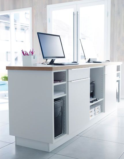 White kitchen cabinets with doors, drawers and worktop used as a front desk.  Definitely doing this. Ikea Reception Desk, Front Desk Design, Ikea Office, Retail Counter, System Furniture, Store Design Boutique, Ikea Desk, Pharmacy Design, Store Interiors