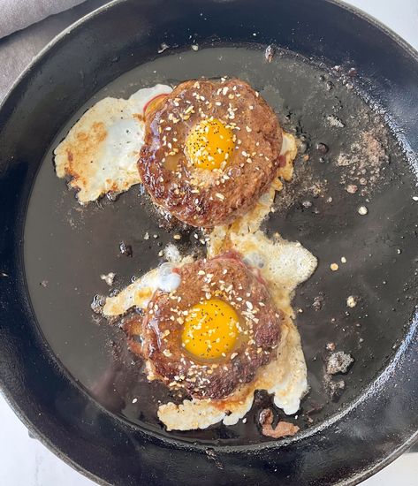 There is a large black iron skillet with two beef patties shaped in the form of a ring cooking in it. There is a cracked raw egg in the center of each patty. There is seasoning sprinkled over the eggs. Egg Breakfast Sandwich, Egg Sandwich Breakfast, Beef Patties, Breakfast Burger, Beef Patty, Egg Breakfast, Delicious Breakfast, Iron Skillet, An Egg