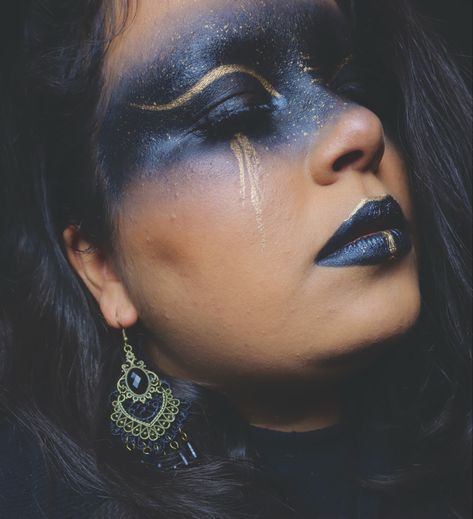 Black across eyes with gold cut crease 
Gold tears and lips are black with gold around top of lip and gold line down lower lip Gold Witch Makeup, Black And Gold Halloween Makeup, Black And Gold Skeleton Makeup, Black And Gold Makeup Aesthetic, Gold Tears, Black And Gold Fairy Makeup, Black Fae Day, Gold Leaf Makeup Looks, Gold Tears Makeup