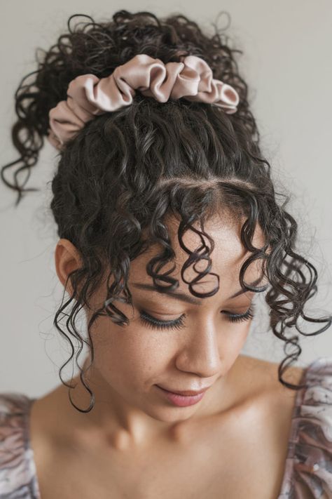 Throw your long layered curls into a messy bun and secure it with a colorful scrunchie for a playful touch. The scrunchie not only holds your curls in place but also adds a fun and youthful vibe. It�s the perfect accessory for a casual, laid-back day. Bun With A Scrunchie, Hair With Accessories, Long Layered Hairstyles, Long Layered Curly Hair, Colorful Scrunchie, Half Up Curls, Curly Layers, Messy Curly Bun, Layered Curls