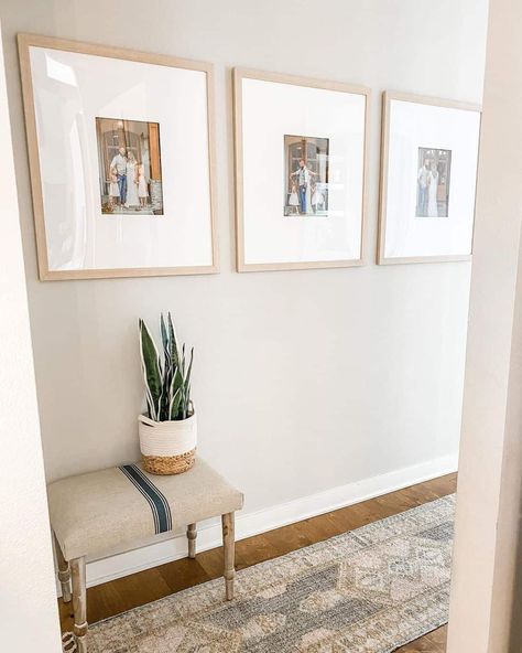 A hallway showcases three family photos in identical light wood frames and large white mats. These are hung above a small vintage bench with a potted plant and traditional style runner on hardwood floors. Family Picture Wall Ideas, Gallery Wall Lighting, Family Picture Wall, Family Photo Gallery Wall, Picture Wall Ideas, Hallway Pictures, Three Family, Family Gallery Wall, Large Hallway