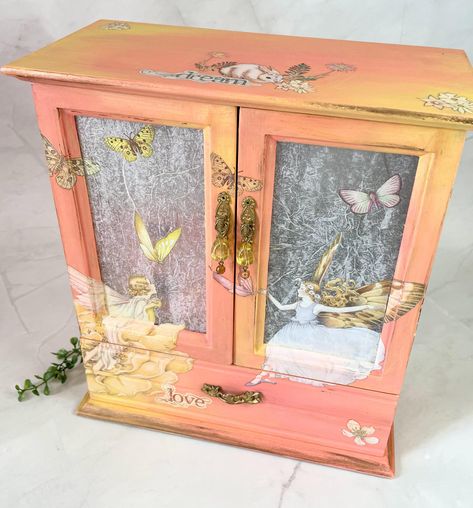 This Inspirational Fairy Garden pattern up-cycled jewelry box will delight that special someone. Decked out in every possible way.   Painted in a blended technique to accompany the transfer design. Colors of yellow, peach, pink, white and Pearlizing Glaze. The Jewelry Box measures: 10" wide 11" tall 5" deep 3 Drawers - Painted with transfers   - 2 Small draws  - 1 Large Drawer Glass door w/ Necklace hanging spinner and Ring storage inside Upcycle Jewelry Box, W Necklace, Furniture Redos, Painted Jewelry Boxes, Scrap Art, Paint Techniques, Ring Storage, Garden Pattern, Jewelry Organizer Diy