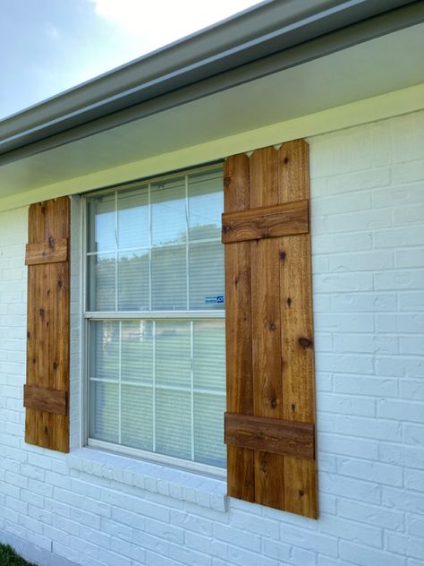 DIY shutters, made with cedar fence pickets, and hellmans clear sealer. Cedar Wood Shutters, Cedar Board And Batten Shutters, Wooden Outdoor Window Shutters, Farmhouse Wooden Shutters, White Brick House Cedar Shutters, Cedar Shutters On Brick House, White Brick House With Cedar Shutters, Barnwood Shutters Exterior, Rustic Wooden Shutters Exterior