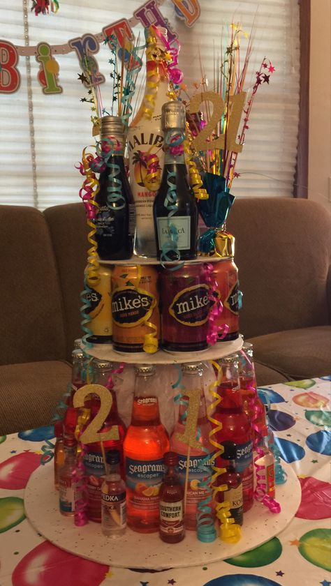 I used wilton cake cardboards for the tiers and covered them in tissue paper. Bottles on the bottom with mini alcohol bottles between,cans in the middle, and top was mini wine bottles and a malibu. Decorated with curling ribbon and 21 numbers and sparklers from balloon weights. Alcohol Bottle Cake, Cakes With Bottles On Top, Alcohol Cake Tower, 21st Birthday Cake With Alcohol Bottles, Cake With Mini Liquor Bottles, Alcohol Tower 21st Birthday, 21st Birthday Liquor Bouquet, Liquor Bottle Cake, 21st Birthday Cake Alcohol