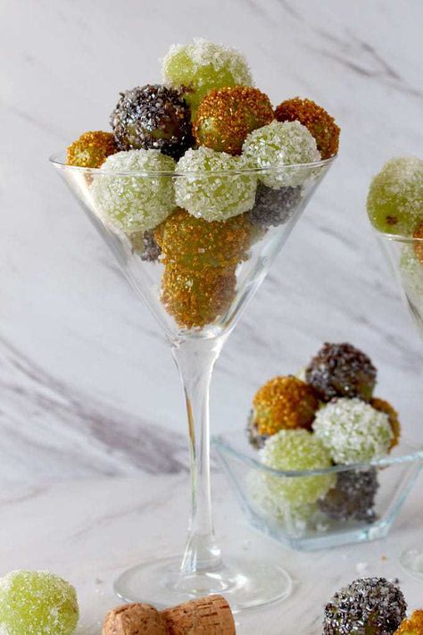 Close up view of a Martini glass filled with sugared grapes in gold, white and silver next to a small square glass bowl filled also with candied grapes Appetizers In Martini Glasses, Martini Party Appetizers, Spiked Grapes, Martini Party Ideas Food, Martini Glass Appetizers, Nye Appetizers, Candied Grapes, Martini Party, Sugared Grapes