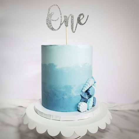 This blue ombre cake was made over the weekend for a very special little ones 1st Birthday! The party had a beach theme ⛱ so I decided to make some chocolate seashells in various shades of blue to add to the cake. It's giving me major ocean vibes! 🌊 What do you think? . . . Colours: @colourmill Cake topper: @etsy Icing comb: @shoptheflourgirl . . . #ombrecake #ombrecakes #blue #beachcake #cakeinspo #cakedecorating #instagood #cakesofinstagram #cakeartists #bakersspotlight #dessert #sweet Blue Ombre Cake Ideas, Blue Beach Cake, Blue Colour Cake, Blue 1st Birthday Cake, Ombre Cake Ideas, Shades Of Blue Cake, Blue Buttercream Cake, 1st Birthday Cake Boy, Hombre Cake