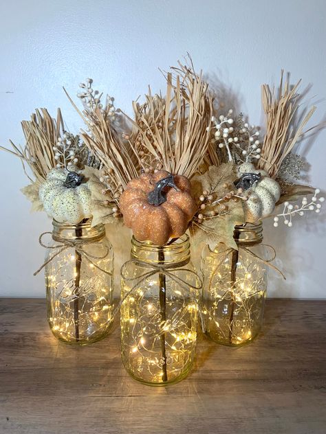 These Fall Mason Jar Lighted Centerpieces are a perfect addition to your seasonal decor! Great for Fall table decor or Thanksgiving centerpieces.  This set includes 3 Quart size Ball mason jars with fall arrangements.   Each floral arrangement will include two brown paper-wrapped stem with an orange pumpkin, berries, maple leaves and raffia and one paper-wrapped stem with a cream pumpkin, berries, maple leaves and raffia and one cream  A piece on twine will be tied to the top of each jar and a 7 Fall Mason Jar Centerpieces, Fall Wedding Decor, Warm White Fairy Lights, Fall Mason Jars, Lighted Centerpieces, Fall Table Centerpieces, Tafel Decor, Jar Centerpieces, Pumpkin Fall Decor