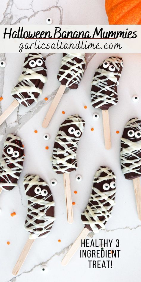 Banana mummies arranged on a white countertop. Ghost Banana Pops, Halloween Fruit Treats For School, Halloween Festive Food, Daycare Halloween Party Food, Halloween Bakes Kids, Kid Halloween Party Food Ideas, Banana Halloween Treats, Halloween Party Fruit Ideas, Halloween Mummy Food