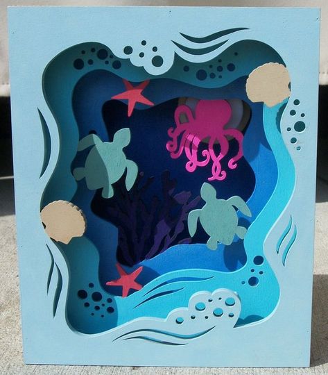 Wood box with various tones of blue on each panel depicts under the sea scene of beige scallop shells, blue tone waves, salmon-colored starfish, sea green sea turtles, pink octopus, and deep purple coral.  Second photo shows close-up of floor of wood box.  The floor is painted in blue with a sea glass effect of glitter pieces. Easy Kids Art Projects, Tunnel Book, Cutout Art, Paper Cutout Art, Murals For Kids, 3d Paper Art, Pop Up Art, Easy Pixel Art, Paper Artwork