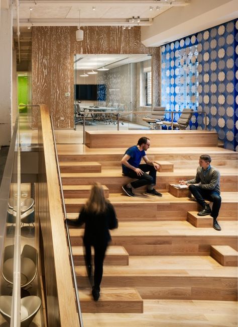 The heart of Pandora’s new office in Midtown Manhattan is a bright, double-height space first visible through a low, compressed entry. This central space provides a physical connection between the two floors via the grand stair on one side and takes advantage of the full height of both floors – about 25 feet – with a large screen made of translucent circular discs, elegantly coupled with figured aluminum hooks backed by a blue theatrical scrim. Google Office, New York Office, Stairs Architecture, Banda Aceh, Corporate Interiors, Office Seating, Workplace Design, Architecture Office, Hospitality Design