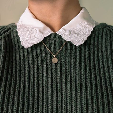 This photo shows the area of a body below the chin and just above the chest. It's zoomed in to show the texture on the dark green, cable-knit sweater worn over a cream-colored button down with swirly embroidery on the collar. Underneath the collar there is a dainty gold chain that hangs down with a gold circle stamped with the letter 'L'. This image is an emphasis on cozy textures. Collar Over Sweater, Collared Shirt Under Sweater Outfit, Sweater And Button Up Outfit, Collar Shirt Under Sweater Outfits, Collar Under Sweater Outfit, Collared Shirt With Sweater, Collard Shirt Under Sweater, Shirt Over Sweater, Collar Under Shirt