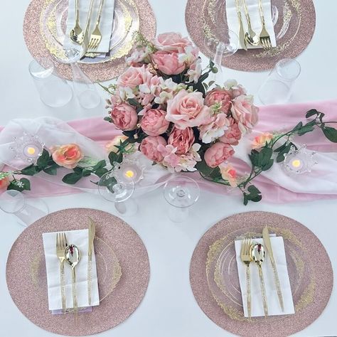 Indulge in the allure of an appealing wedding table setup. Pink and white sheer organza table runners, adorned with a faux leaf garland, create a whimsical touch atop the pristine white polyester tablecloth. Clear round charger plates rest elegantly on rose gold shimmer tablemats, adding a touch of glamour. Gleaming gold plastic utensils and crisp white dinner napkins grace the charger plates, inviting guests to partake in a delightful feast. Organza Table Runner, Event Decor Ideas, Party Decorations Table, Wedding Table Setup, Flowers Candles, White Dinner, Plastic Utensils, Faux Leaf, Leaf Garland