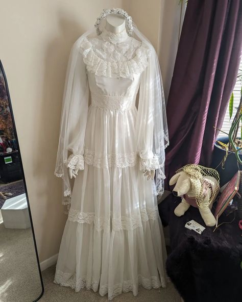 This incredible vintage wedding dress is still looking for her new home! Worn in the early eighties, this 70s inspired piece has a gorgeous matching veil with a floral crown and an underskirt to give that amazing skirt it's proper full shape. It has been incredibly well preserved and the tiny bits of discolouration are very mild and unnoticeable. I think this dress is perfect for a whimsical fantasy wedding or even a spooky goth wedding. It does look a bit spooky at night in the corner of ... 70s Wedding Dress, Goth Wedding, Vintage Wedding Dress, Fairy Wedding, Fantasy Wedding, 70s Inspired, Floral Crown, Wedding Dresses Vintage, Night In