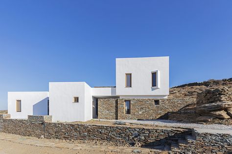 Inspired by the complexity and the volumes of the Cycladic architecture, the summer house of totally 250 m2 unfolds around a hillside of the island of Sifnos looking towards the charming valley of Agios Ioannis and the Aegean Sea. Whitewashed Stone, Exterior Render, Built In Sofa, Greek House, Greek Isles, Dry Stone Wall, Stone Cladding, Exposed Concrete, Beautiful Vacations