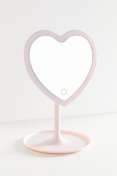 Show your shelf some love with this standing LED mirror in the shape of a heart. Features a catch-all tray base to store your favorite jewelry, makeup and skincare. Exclusively available at UO.Features. LED light Smart touch button Storage tray for accessories 180° rotation Battery operated (requires 3 AAA batteries)Content + Care. 100% Plastic Wipe clean ImportedSize. Dimensions: 7.7”w x 11.4”h Prwppy Mirror, Urban Heart Mirror, Makeup Small Mirror, Cite Mirrors, Preppy Small Mirrors, Heart Makeup Mirror, Led Small Mirror, Small Mirror With Lights, Small Light Up Mirror