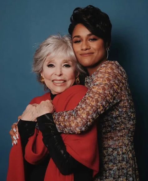 ariana debose, wearing a long sleeved brown, yellow, red and green dress and has white nails. she has her arms wrapped around rita moreno, wearing a red poncho over a black long sleeved blouse. moreno clutches onto debose, both smiling widely. Anita West Side Story, West Side Story Movie, Ariana Debose, Isadora Duncan, Ansel Elgort, Rita Moreno, Frederick Douglass, Theatre Nerds, West Side Story