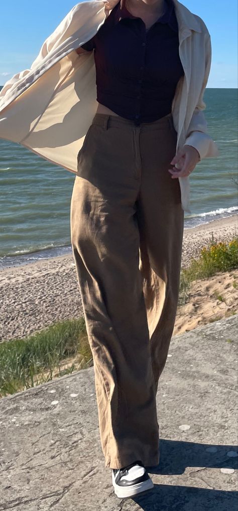 Woman standing by the sea. windy, flowy clothing, beige colors. Asymmetric corset top, wide-end pants. Blue/ brown color palette/light setting Dark Academia 90s Aesthetic, Outfit Ideas Old School, Dark Academia Outfit Inspo Summer, Modern Light Academia Outfits, Summer Fits Dark Academia, Dark Academia Travel Outfits, Summer Outfit Academia, Old Fashion Summer Outfits, Old Clothing Aesthetic