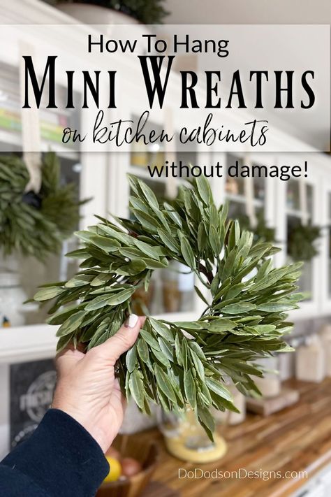 It's time to decorate for Christmas! Want to add a little holiday flair to your kitchen cabinets? Learn how to hang mini wreaths quickly and easily without damaging your cabinets. My farmhouse never looked more charming. Small Wreaths On Kitchen Cabinets, Small Christmas Wreaths On Cabinets, Wreaths On Windows Indoors, Window Wreaths Indoor, Small Christmas Wreaths For Kitchen Cabinets, Wreath In Kitchen, Kitchen Window Wreath, Mini Wreaths On Kitchen Cabinets, Mini Wreaths On Kitchen Cabinets Farmhouse